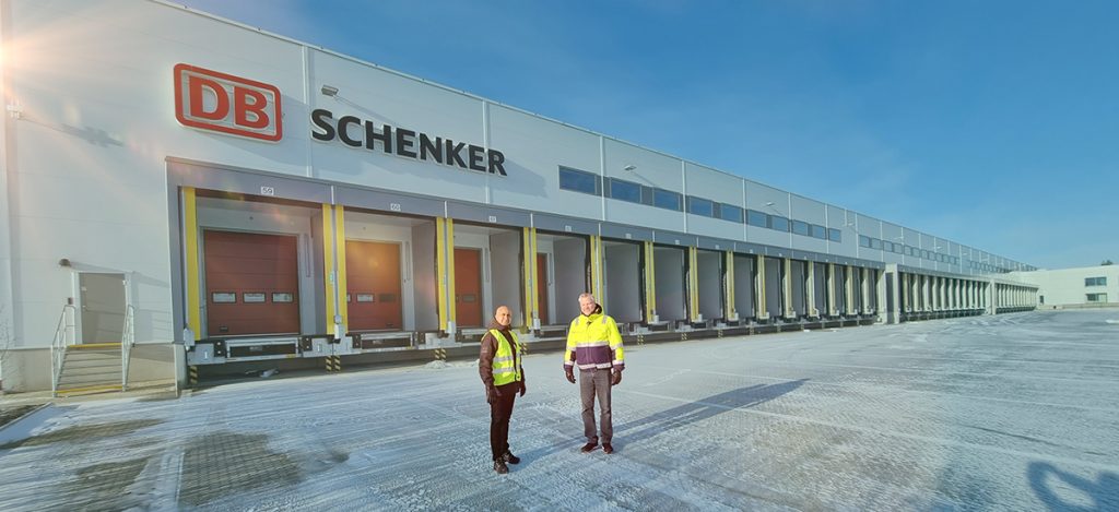 Schenkers nya terminal och två personer framför terminalen