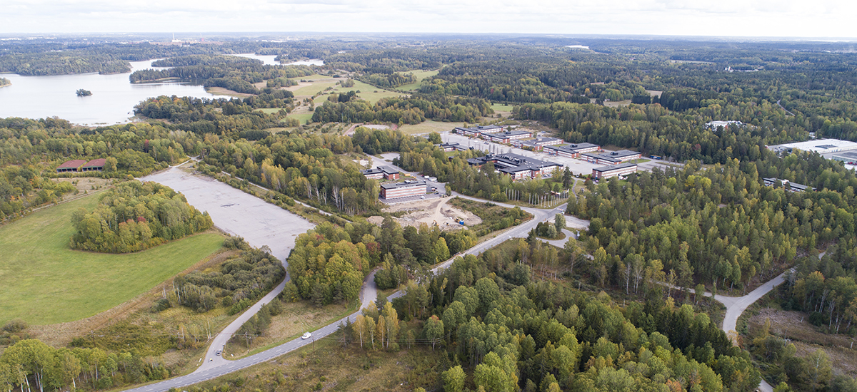 flygbild över området i Stockholm syd som visar industribyggnader, träd och fält.